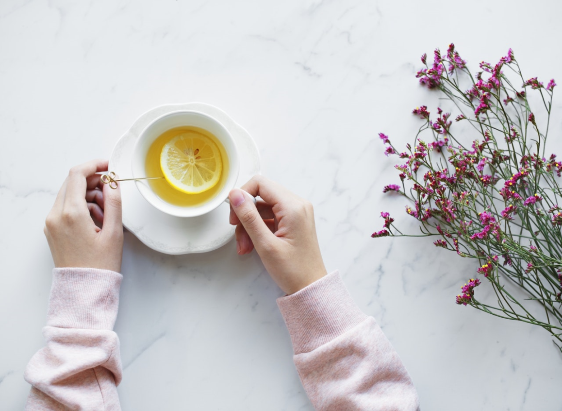 Lady holding a cup of tea on white marble table